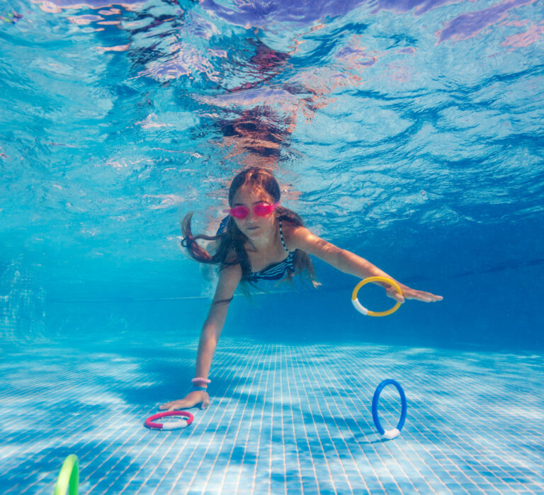 Girl under water, diving for water rings, swimming