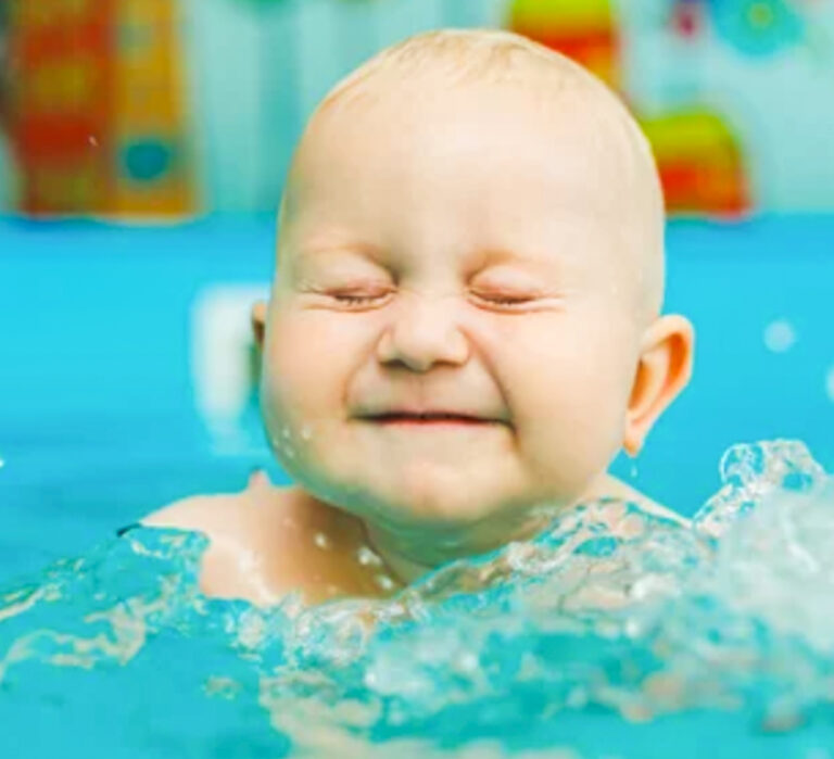 Baby jumping in pool having fun at aquatics mobile swim lesson